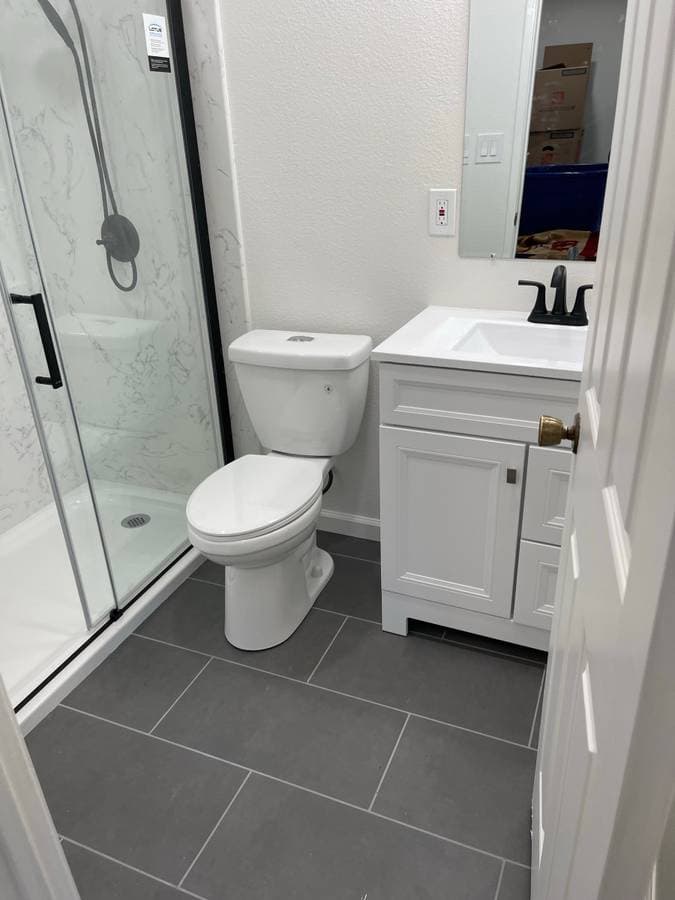 Freshly remodeled and painted bathroom with white walls and gray floor tile